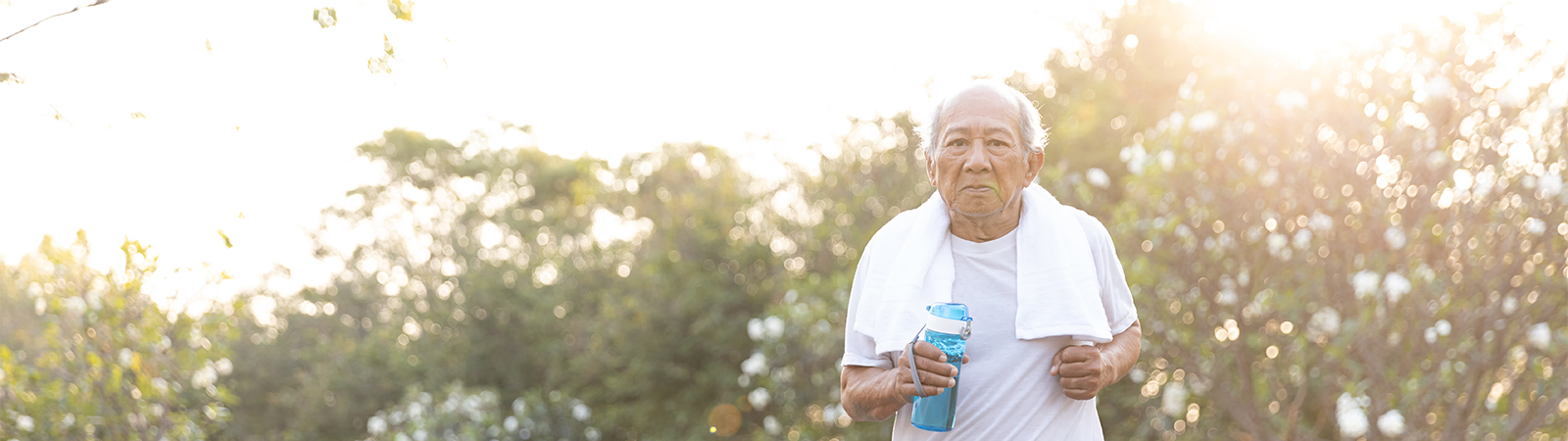 Senior man staying hydrated after outdoor exercise in sunny park, promoting active aging and wellness