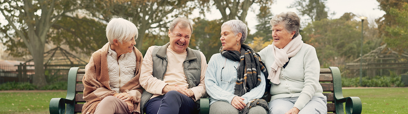 Active seniors sharing laughs on outdoor bench, highlighting social wellness and joyful aging lifestyle