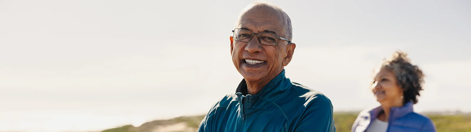 Active senior man with glasses smiling outdoors, showcasing healthy aging, fitness and resilience goals