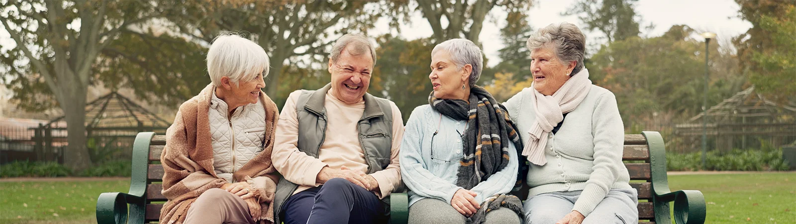 Active seniors sharing laughs on outdoor bench, highlighting social wellness and joyful aging lifestyle